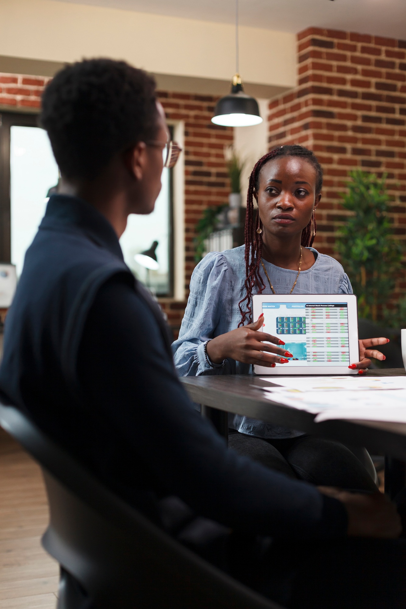 African american business woman presenting to coworker accounting documentation statistics data